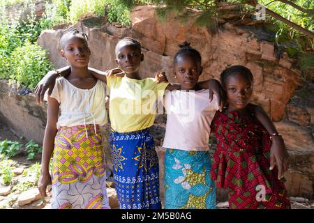 Ripresa all'aperto di quattro giovani sorelle africane in posa con le braccia intorno alle spalle guardando la telecamera con espressioni serie e orgogliose sul loro Foto Stock