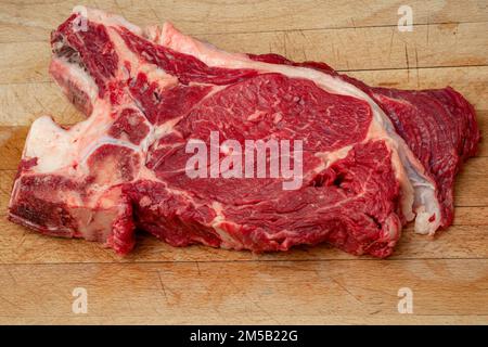 Alimenti ad alto contenuto proteico, carni rosse sane e dieta carnivore concetto con grande mandrino di carne magra muscolare e ossa su legno rustico tagliere bordo Foto Stock