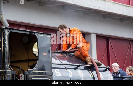 i meccanici riparano una vecchia locomotiva a vapore in un deposito Foto Stock