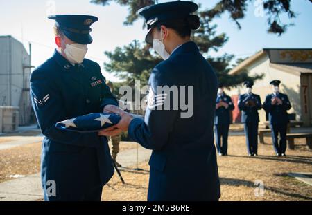 Staff Sgt. Phu San e Airman First Class Anthony Paree, 8th Fighter Wing base Honor Guardsmen, piegare e ispezionare una bandiera americana in preparazione per il ritiro alla base aerea di Kunsan, Repubblica di Corea, 18 febbraio 2022. Quando una bandiera americana è ritenuta non più riparabile, deve essere onorata con una cerimonia di pensione e bruciata. Foto Stock