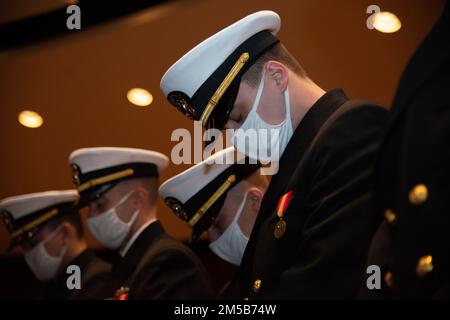 NEWPORT, RI (18 febbraio 2022) Officer Candidate School (OCS) classe 06-22 studenti al Officer Training Command Newport (OCCN), Newport, Rhode Island, si abbassano le teste per l'invocazione durante la cerimonia di laurea, 18 febbraio. OCS sviluppa civili e marinai della flotta in ufficiali recentemente commissionati moralmente, mentalmente e fisicamente, mentre instillano loro con i più alti ideali di onore, coraggio e impegno per il servizio nella flotta come ufficiali navali. Foto Stock