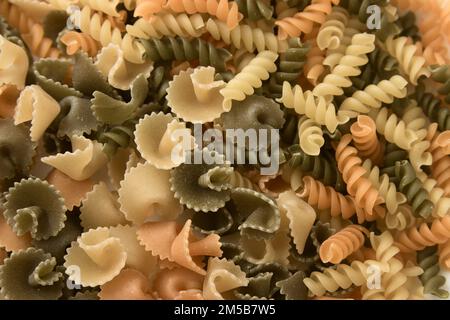 Primo piano di un piatto con pasta corta di vari colori e forme come fusilli e margherite Foto Stock