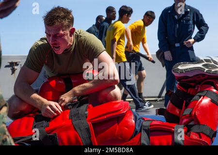 STATI UNITI Ethan Huey, un leader della squadra con 3rd Light Armored Reconnaissance (LAR), offre richieste durante un corso di spray OC, a bordo di USS Green Bay, Philippine Sea, 19 febbraio 2022. Il MEU 31st opera a bordo delle navi dell'America Amphibious Strike Group nell'area operativa della flotta 7th per migliorare l'interoperabilità con alleati e partner e servire da pronta risposta per difendere la pace e la stabilità nella regione Indo-Pacifico. Foto Stock