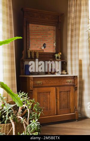 Piante verdi e antico comò in legno nella camera da letto principale al piano superiore all'interno di casa di legno stile cottage paese. Foto Stock