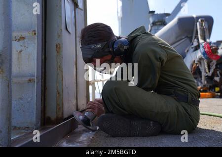 OCEANO PACIFICO (22 febbraio 2022) Aviazione Ordnanceman 3rd Classe Zachary Burgess, un nativo di Baytown, Texas, gestisce un smerigliatore angolare a bordo di Harpers Ferry-classe nave anfibio sbarco porto USS Pearl Harbor (LSD 52), nell'Oceano Pacifico, 22 febbraio 2022. Marinai e marines dell'Essex Amphhibious Ready Group (ARG) e dell'unità marittima di spedizione 11th (MEU) stanno conducendo operazioni di routine nella flotta degli Stati Uniti 3rd. Foto Stock