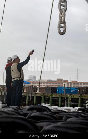 220223-N-HA192-1060 NORFOLK, VIRGINIA. (23 febbraio 2022) - i marinai assegnati alla nave d'assalto anfibio USS Bataan (LHD 5) effettuano il mantenimento della conservazione sulla catena di ancoraggio lato porto 23 2022 febbraio. Bataan è casa presso la Naval Station Norfolk. Foto Stock