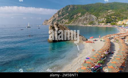 Spiaggia di ciottoli Monterosso vacanze cinque Terre Monterosso al Mare le sedie a sdraio e gli ombrelloni riempiono la spiaggia di Fegina, Monterosso, parte delle cinque Terre in una giornata di sole Foto Stock