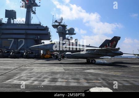 MARE DELLE FILIPPINE (24 febbraio 2022) un F/A-18E Super Hornet, assegnato ai 'Tophatters' di Strike Fighter Squadron (VFA) 14, fa un atterraggio arrestato sul ponte di volo della portaerei di classe Nimitz USS Abraham Lincoln (CVN 72). Abraham Lincoln Strike Group è in fase di implementazione pianificata nell'area delle operazioni della flotta 7th degli Stati Uniti per migliorare l'interoperabilità attraverso alleanze e partnership e al tempo stesso fungere da forza di risposta pronta a sostegno di una regione indomPacifico libera e aperta. Foto Stock