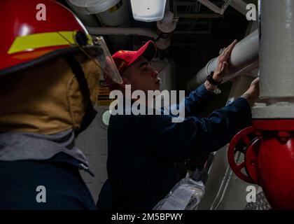GULF OF OMAN (24 febbraio 2022) Damage Controlman 2nd Class Derek PoE, a destra, insegna a Gunner’s Mate 3rd Class Christopher Hart come utilizzare patch di riparazione attivate dall’acqua di emergenza durante un trapano di controllo dei danni a bordo del cacciatorpediniere missilistico guidato USS Gridley (DDG 101) nel Golfo di Oman, 24 febbraio. Gridley è schierato nell'area delle operazioni della flotta degli Stati Uniti 5th a sostegno delle operazioni navali per assicurare la stabilità e la sicurezza marittima nella regione centrale, collegando il Mediterraneo e il Pacifico attraverso l'Oceano Indiano occidentale e tre punti di arresto strategici. Foto Stock
