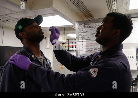 OCEANO INDIANO (24 febbraio 2022) Ospedale Corpsman 2nd Classe David Worrell, da Jacksonville, Florida, test Capo Fire Controlman Travis Taylor, da Newport News, Virginia, per COVID-19 in medicina a bordo della Arleigh Burke-classe cacciatorpediniere-missile guidato USS Fitzgerald (DDG 62). Fitzgerald è in fase di implementazione programmata nell'area delle operazioni della flotta 7th degli Stati Uniti per migliorare l'interoperabilità con alleanze e partnership e allo stesso tempo fungere da forza di pronto intervento a sostegno di una regione indomPacifico libera e aperta. Foto Stock
