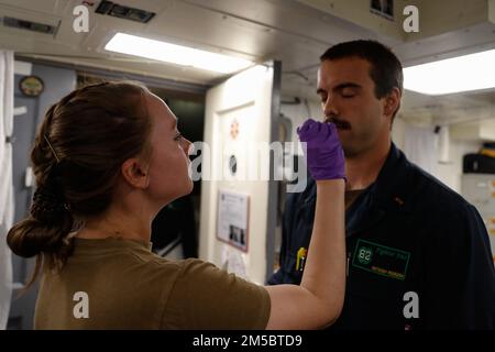 OCEANO INDIANO (24 febbraio 2022) Ospedale Corpsman 2nd Classe Cortland Williams, da Nashville, Tenn., test Ens. Anthony Pedreira, di Seattle, per COVID-19 in medicina a bordo del cacciatorpediniere missilistico guidato di classe Arleigh Burke USS Fitzgerald (DDG 62). Fitzgerald è in fase di implementazione programmata nell'area delle operazioni della flotta 7th degli Stati Uniti per migliorare l'interoperabilità con alleanze e partnership e allo stesso tempo fungere da forza di pronto intervento a sostegno di una regione indomPacifico libera e aperta. Foto Stock