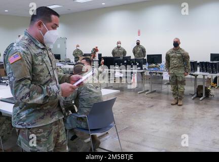 Luis Martínez, sergente dell'operazione della Joint Task Force - Porto Rico, presenta ai soldati una prestazione eccezionale durante la risposta del COVID-19 a Fort Buchanan, Porto Rico, 24 febbraio 2022. Il vicedirettore della Guardia Nazionale dell'Esercito visitò l'isola e riconobbe questi soldati con una moneta di eccellenza per essersi levato in piedi nei suoi doveri durante gli sforzi contro il COVID-19. Foto Stock