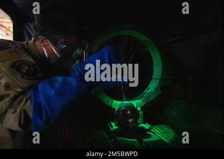 Airman 1st Classe Melquan Madison, 4th manutenzione di apparecchiature Squadron ispettore non distruttivo, cerca difetti su un pezzo di apparecchiature di aeromobili dopo un bagno di particelle magnetiche alla Seymour Johnson Air Force base, North Carolina, 24 febbraio 2022. Le particelle di ferro fluorescenti nella miscela diventano magnetizzate all'interno di crepe o difetti che le rendono visibili e si illuminano sotto una luce nera. Foto Stock