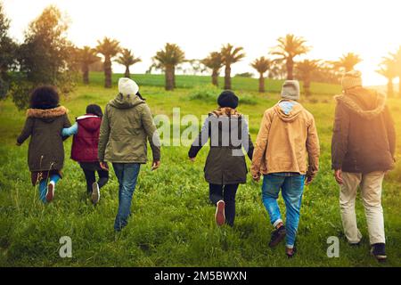 Non tutti coloro che vagano sono persi. Ripresa da dietro di un gruppo di amici che camminano in un campo insieme. Foto Stock