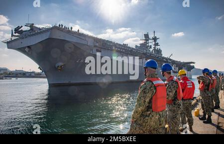 I marinai assegnati al comandante, attività della flotta Sasebo (CFAS) si preparano ad aiutare a ormeggiare la nave d'assalto anfibio USS America (LHA 6) al 25 febbraio 2022. Per 75 anni, CFAS ha fornito, mantenuto e gestito strutture e servizi di base per potenziare le forze alleate e statunitensi schierate in futuro, fornendo al contempo un supporto superiore alle loro famiglie e alla comunità. Foto Stock