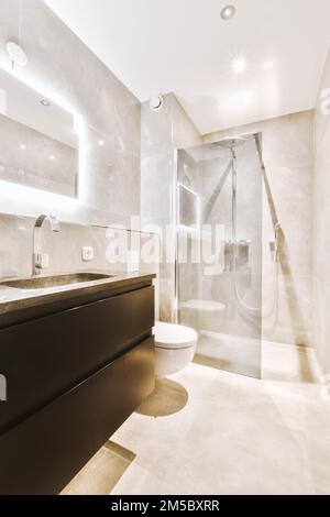 un bagno moderno con pareti e pavimento in marmo bianco, unitamente ad una cabina doccia sul lato destro Foto Stock