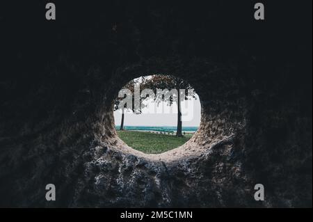 Vista di due alberi decidui attraverso un buco in una pietra sulla Kronsberg, Hannover, bassa Sassonia, Germania Foto Stock