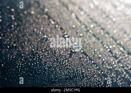 Condensa o gocce di pioggia sul finestrino posteriore della vettura in inverno in una mattina di sole Foto Stock