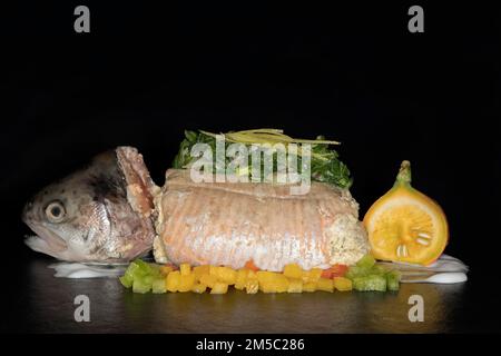 Trota di salmone ripiena e al vapore, con bietole, limoni, peperoni a dadini, fichi decorati e mini Hakkaido, fotografia alimentare con sfondo nero Foto Stock