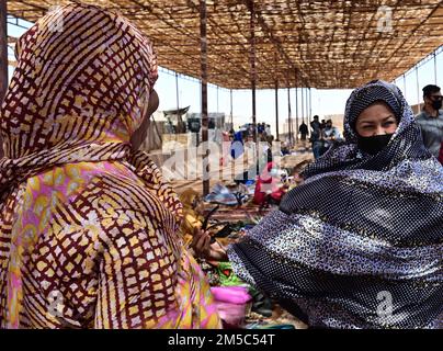 STATI UNITI Maribel Seegmiller (a destra), 724th base aerea espeditativa Squadron direttore delle operazioni, prova su un abito tradizionale africano durante un bazar alla base aerea nigerien 201, Agadez, Niger, 27 febbraio 2022. Oltre 40 venditori locali dalla città di Agadez e villaggi circostanti hanno frequentato il bazar, vendendo vari beni. I membri del servizio negli Stati Uniti hanno acquistato una merce del valore di circa 10.532.000 franchi CFA dell'Africa occidentale ($18K USD). Eventi come questi migliorano le relazioni tra Stati Uniti e Niger e stimolano lo sviluppo economico locale. Foto Stock