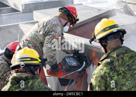 STATI UNITI Personale dell'esercito Sgt. Timothy Armstrong, leader del team di ricerca ed estrazione, 861st Engineer Company, New England Chemical, Biological, Radiological, Nucleare, pacchetto di forza di risposta migliorata esplosiva (CERFP), la Guardia nazionale dell'esercito del Rhode Island, con sede a East Greenwich, R.I. utilizza una motosega per tagliare cemento attraverso una lastra di cemento durante la ricerca di forze congiunte e l'addestramento all'estrazione come parte dell'esercizio Arctic Eagle-Patriot 22 presso il centro di addestramento antincendio di Anchorage, in Alaska, Marzo 1, 2022. Esercizio congiunto Arctic Eagle-Patriot 2022 aumenta la capacità operativa della Guardia Nazionale Foto Stock