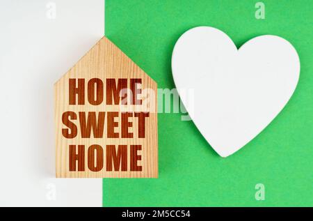 Concetto aziendale. Su una superficie bianco-verde, un cuore e una casa con l'iscrizione - Casa dolce casa Foto Stock