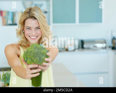 I benefici per la salute sono infiniti. Ritratto di una giovane donna felice che tiene una scossa di broccoli. Foto Stock