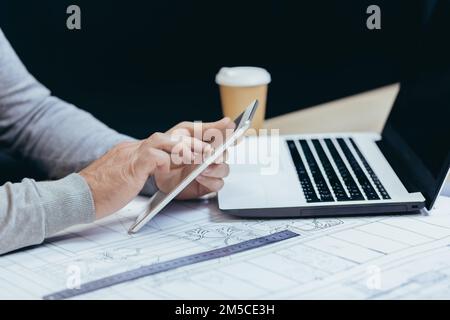Foto ravvicinata delle mani di un architetto designer maschile che lavora con un tablet all'interno di un ufficio moderno. Foto Stock
