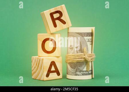 Concetto aziendale. Su una superficie verde, dollari e cubi con l'iscrizione - ROA Foto Stock