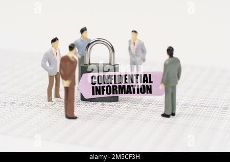 Il concetto di sicurezza nelle imprese. Ci sono cifre di persone nei rapporti commerciali, un lucchetto con un adesivo su cui è scritto - Confidential i Foto Stock