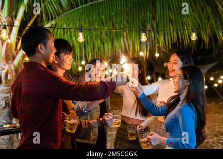 I giovani asiatici festeggiano felicemente le scintille in festa Foto Stock