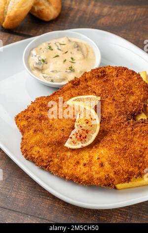 Schnitzel di pollo con burro e insalata di patate su piatto di porcellana bianca Foto Stock