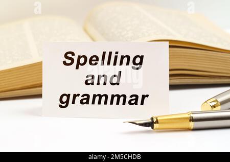 Concetto di istruzione. Sullo sfondo del libro si trova una penna e un biglietto da visita con l'iscrizione - ortografia e grammatica Foto Stock