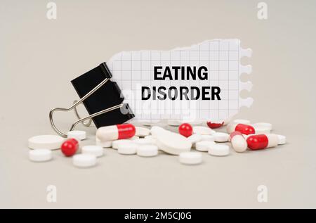 Concetto medico. Tra le compresse e le capsule è una clip con carta su cui è scritto - mangiare disturbo Foto Stock