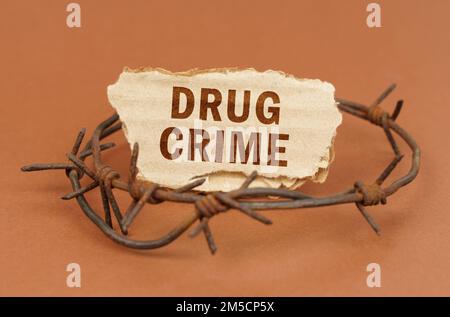 Il concetto di diritto e criminalità. Su una superficie marrone, filo spinato e un cartoncino con l'iscrizione - crimine di droga Foto Stock