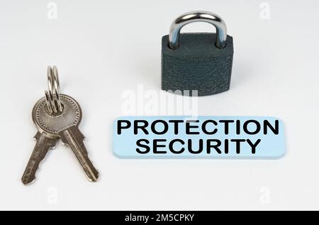 Il concetto di sicurezza nelle imprese. Su una superficie bianca vi è una serratura, chiavi e un segno blu con l'iscrizione - protezione di sicurezza Foto Stock