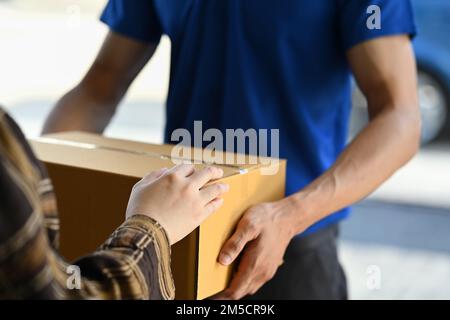 Immagine ritagliata di una cliente femmina che riceve il pacchetto dall'addetto alla consegna alla porta Foto Stock