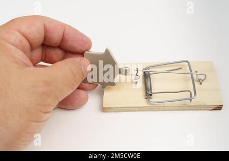 Investimenti e rischi bancari. La mano di un uomo sta cercando di estrarre una figurina metallica di una casa da un mousetrap. Foto Stock