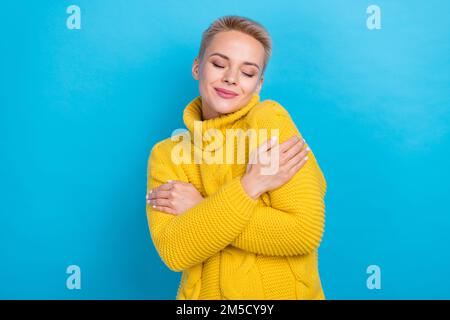 Foto di bella signora vestita bella comfort maglione abbracciare se stessa immaginare sogno vacanza atmosfera isolato su sfondo di colore blu Foto Stock