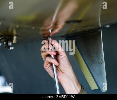 STATI UNITI Personale dell'aeronautica Sgt. Jacob Smith, 555th unità di manutenzione degli aerei F-16 Capo equipaggio Fighting Falcon, svita una vite da un pannello su un F-16 presso Aviano Air base, Italia, 2 marzo 2022. Il mantenimento effettuato garantisce il continuo sostegno alla missione di polizia aerea rafforzata della NATO. Il PAE è una componente di routine e fondamentale del modo in cui la NATO fornisce sicurezza regionale ai suoi membri. Gli Airmen 31st Fighter Wing, dotati di funzionalità multiple, sono pronti ad aiutare gli Stati Uniti Le forze aeree in Europa e le forze aeree in Africa e nei suoi alleati NATO a sostegno delle operazioni in corso attualmente in Europa. Foto Stock