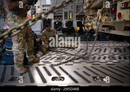 STATI UNITI Marvin Agustin, 621st Contingency Response Squadron facchino aereo, utilizza catene per assicurare il carico a bordo di un C-17 Globemaster III 3 marzo 2022, presso Hunter Army Airfield, Georgia. Gli aerei assegnati al 621st CRS, 321st CRS e 621st Mobility Support Operations Squadron integrati con i soldati assegnati alla 3rd Divisione Fanteria e Arrival Departure Airfield Control Group per il trattamento di carichi, attrezzature e personale per un rapido spiegamento. Foto Stock