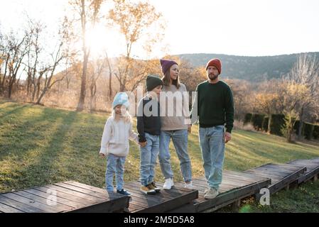 Felice famiglia di padre e madre con i bambini su sfondo autunno natura a scena rustica. Paternità. Foto Stock