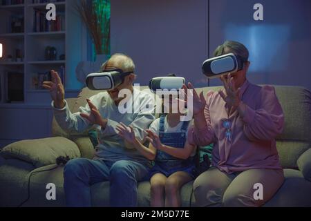 nonna e nonni giocano insieme interessanti videogame utilizzando cuffie per realtà virtuale Foto Stock