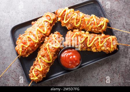 I corn dog coreani o i hot dog coreani sono popolari cibo di strada locale, tipicamente fatto di salsicce o mozzarella su bastoncini di primo piano fritti sul Foto Stock