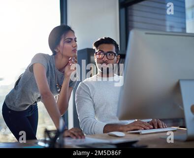Trovare un modo o fare uno. colleghi che cercano di risolvere qualcosa su un computer al lavoro. Foto Stock