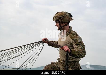 NEGLI STATI UNITI Paracadutista dell'esercito assegnato a 1st Squadrone, 91st reggimento di cavalleria (Airborne) tira le sue linee di sospensione per recuperare il suo paracadute durante un'operazione aerea a fianco di soldati del gruppo delle forze speciali tunisine vicino a Bizerte, Tunisia il 3 marzo 2022. La Brigata Airborne 173rd è la U.S.A. La forza di risposta di contingenza dell'esercito in Europa, che fornisce le forze rapidamente dispiegabili alle aree di responsabilità europee, africane e del comando centrale degli Stati Uniti. Schierata in avanti in Italia e Germania, la brigata si allena regolarmente insieme agli alleati e ai partner della NATO per costruire delle partnership A. Foto Stock