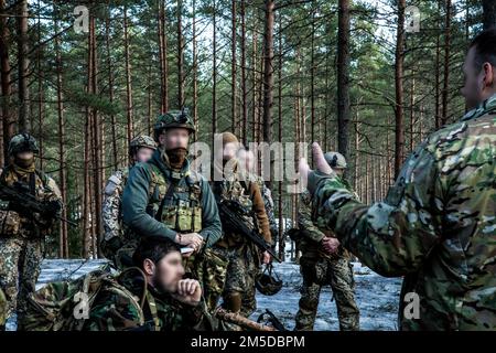 20220303-A-VU095-1303 – STATI UNITI Esercito Verde Beret assegnato a 10th forze speciali Gruppo conduce una revisione dopo l'azione con i soldati della Guardia Nazionale Lettone nelle foreste della Lettonia, 3 marzo 2022. La formazione bilaterale crea interoperabilità con gli alleati della NATO, migliora la preparazione militare e rafforza la fiducia congiunta promuovendo al contempo la pace e la stabilità all'interno della regione. Foto Stock