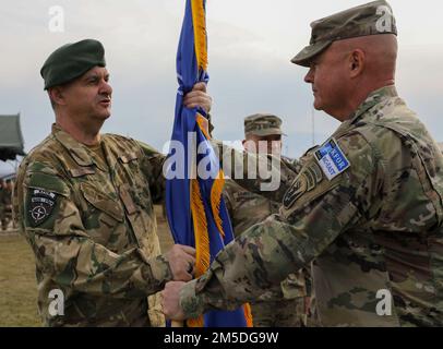 CAMPO BONDSTEEL, Kosovo – col. Brey Hopkins, destra, comandante, 86th squadra di combattimento della Brigata della Fanteria, Guardia Nazionale del Vermont, E il comando regionale della forza del Kosovo uscente - comandante est, passa la bandiera della NATO al maggiore ungherese, il generale Ferenc Kajári, comandante della KFOR, durante la cerimonia di trasferimento dell'autorità della KFOR RC-East a Camp Bondsteel, Kosovo, il 4 marzo 2022. L'IBCT del 86th ha ceduto la responsabilità della KFOR RC-East all'IBCT del 116th, Guardia Nazionale della Virginia, durante la cerimonia di trasferimento dell'autorità. Foto Stock