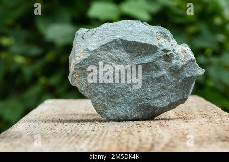 Un pezzo di pietra grigia, ardesia Metamorfica campione su sfondo di legno Foto Stock