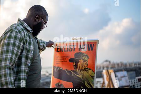 GIBUTI, Gibuti (5 marzo 2022) – Stati Uniti Navy Equipment Operator 3rd Class Gabriel Capers, un velista di Charlotte, N.C., assegnato a Maritime Expeditionary Squadron 10 Bravo Co. Schierato a Camp Lemonnier, Gibuti (CLDJ), guarda un classico poster di reclutamento della Marina visualizzato durante una palla che celebra il 80th° compleanno dei Seabee marzo 5. I partecipanti e gli ospiti onorati hanno celebrato la storia e il patrimonio dei Navy Seabees, ufficialmente istituiti il 5 marzo 1942. Foto Stock